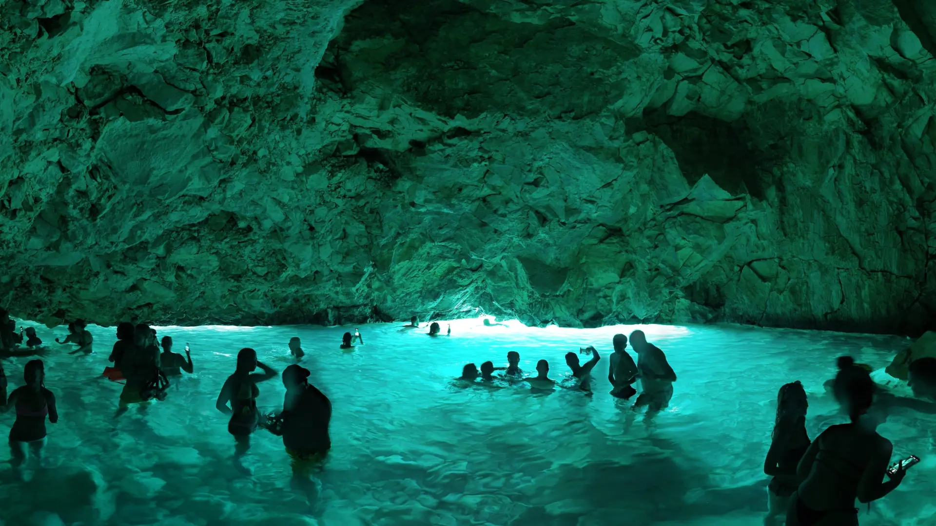 Swimmers in green-blue water inside the Blue Cave, a stop earlier on the same day trip
